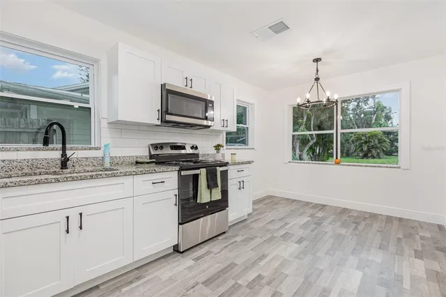 a kitchen with granite countertop a stove a sink and a microwave