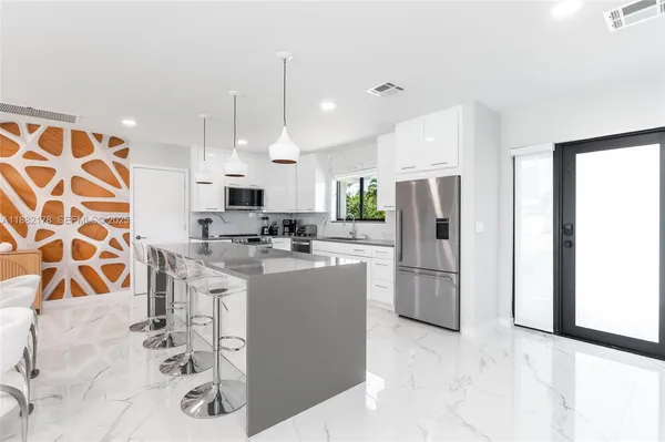 a kitchen with stainless steel appliances kitchen island granite countertop a refrigerator and a sink