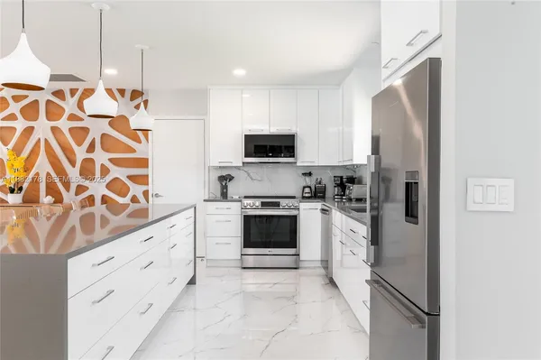 a kitchen with granite countertop white cabinets and stainless steel appliances