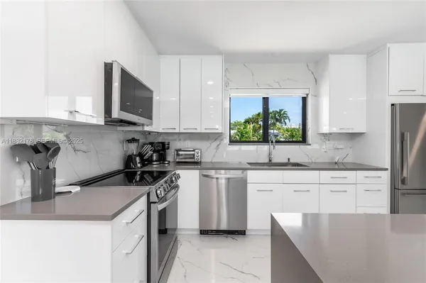 a kitchen with stainless steel appliances granite countertop a stove top oven a sink a microwave and a refrigerator
