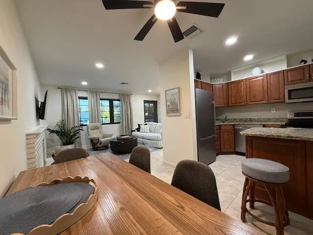 a kitchen with stainless steel appliances kitchen island granite countertop a refrigerator a stove a sink dishwasher a dining table and chairs with wooden floor