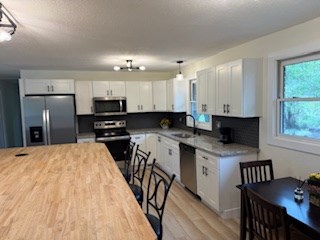 102 Ledford Chapel Road Hayesville, NC 28904 - Photo 11 of 30 a kitchen with stainless steel appliances kitchen island granite countertop a stove a sink a refrigerator a dining table and chairs