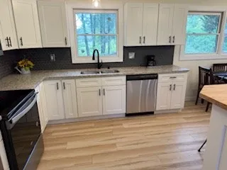 a kitchen with white cabinets sink and window