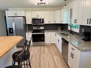 a kitchen with stainless steel appliances granite countertop a stove a sink dishwasher a microwave oven with cabinets and wooden floor