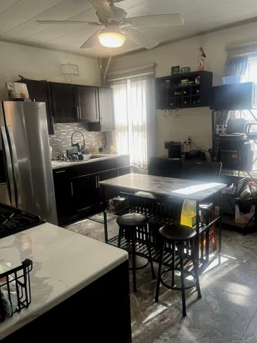 a kitchen with stainless steel appliances kitchen island granite countertop a sink a stove a dining table and chairs