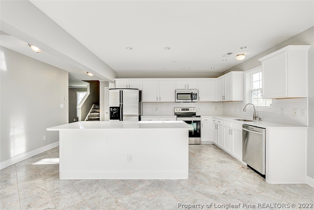 3104 Guiding Light Road Raleigh, NC 27610 - Photo 8 of 36 a large white kitchen with stainless steel appliances granite countertop a stove a sink a refrigerator and white cabinets