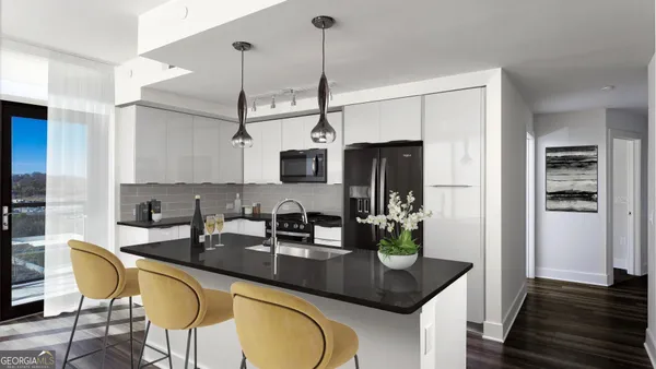 a kitchen with stainless steel appliances granite countertop a sink a microwave refrigerator and chairs