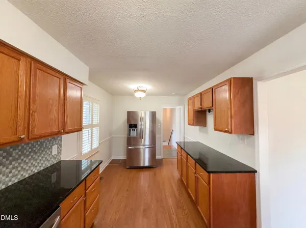 a kitchen with stainless steel appliances kitchen island granite countertop wooden cabinets a sink and a refrigerator