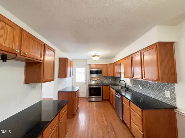 a large kitchen with stainless steel appliances granite countertop a stove a sink dishwasher and a refrigerator
