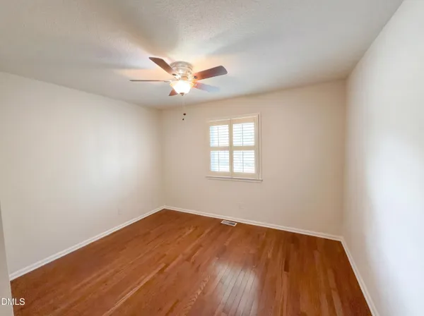 an empty room with a window and a ceiling fan