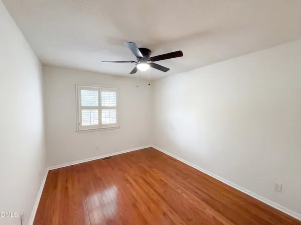 an empty room with a window and a ceiling fan
