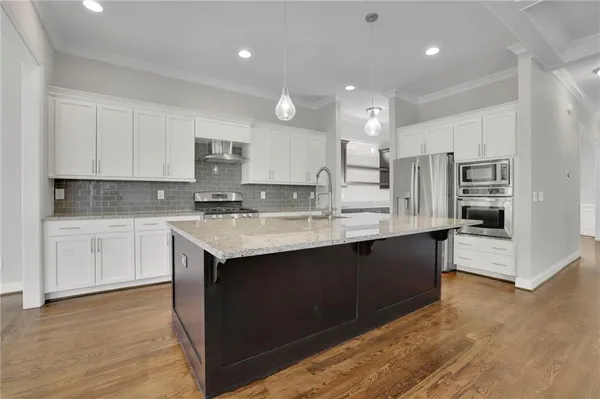 a kitchen with kitchen island granite countertop a sink cabinets and stainless steel appliances
