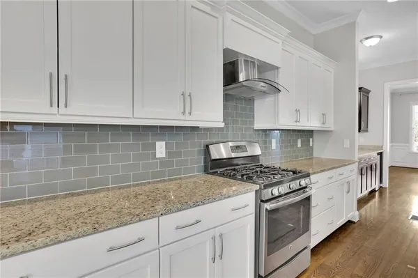a kitchen with granite countertop white cabinets and stainless steel appliances