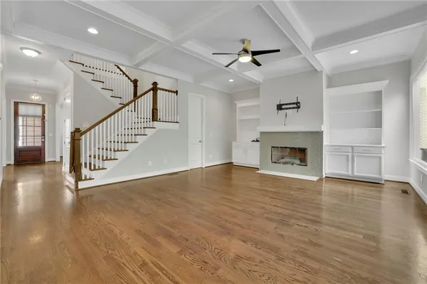 an empty room with wooden floor fireplace and windows