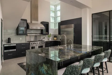 a kitchen with granite countertop kitchen island stainless steel appliances a sink a stove and a refrigerator
