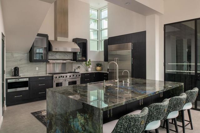 a kitchen with granite countertop kitchen island stainless steel appliances a sink a stove and a refrigerator