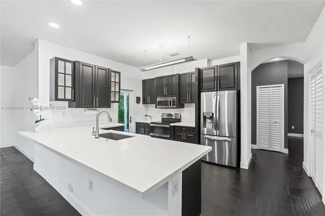 a kitchen with stainless steel appliances a sink stove refrigerator and cabinets