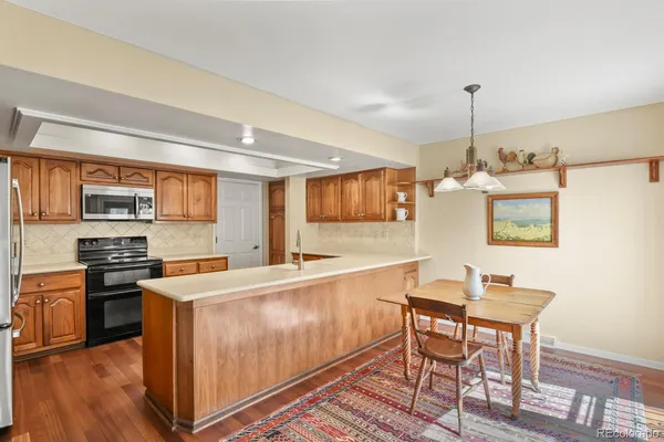 a large kitchen with stainless steel appliances granite countertop a stove a sink dishwasher and a refrigerator with wooden floor