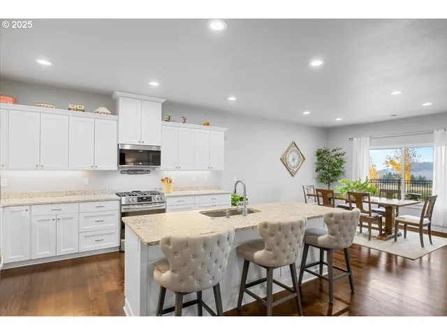 a kitchen with stainless steel appliances kitchen island granite countertop a stove a sink a dining table and chairs