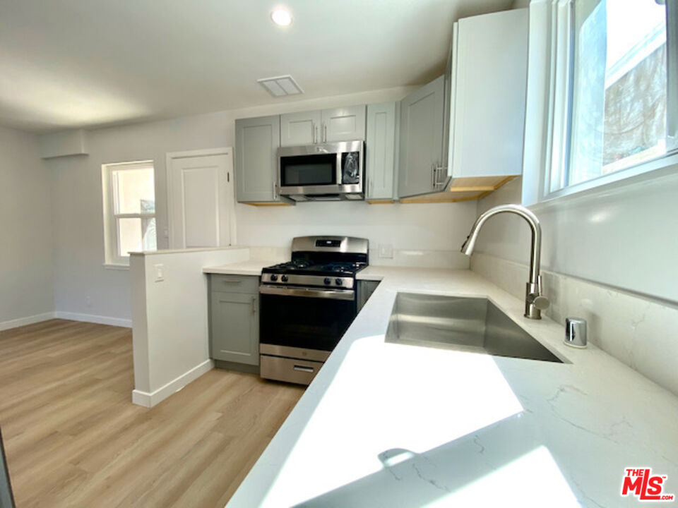 11700 Dorothy Street, Unit 2 Los Angeles, CA 90049 - Photo 11 of 31 a kitchen with stainless steel appliances kitchen island granite countertop a stove a sink and a microwave