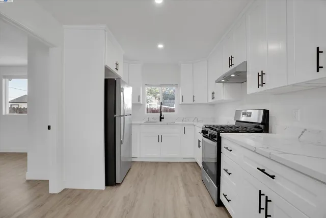 a kitchen with cabinets appliances wooden floor and a window