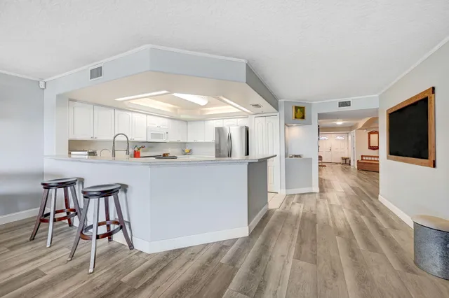 a spacious bedroom with a bed a chandelier and windows