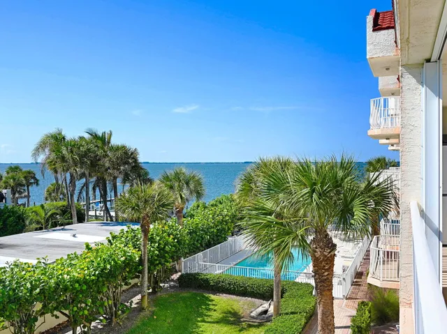 a view of a lake with couches and table with potted plants