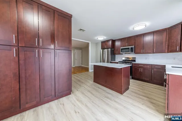 a kitchen with stainless steel appliances granite countertop wooden cabinets a refrigerator and a sink