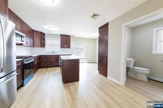 a large open kitchen with stainless steel appliances kitchen island granite countertop a sink and cabinets