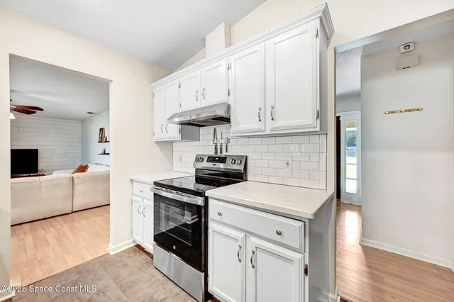 a kitchen with cabinets appliances and wooden floor