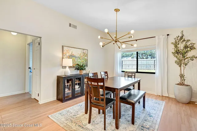 a dining room with furniture a chandelier and wooden floor