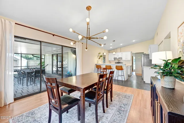 a view of a dining room and livingroom with furniture wooden floor a chandelier