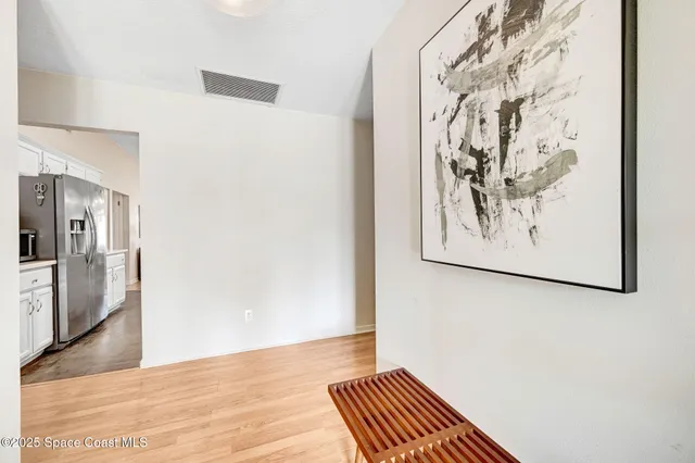 a view of a hallway with wooden floor and a kitchen space