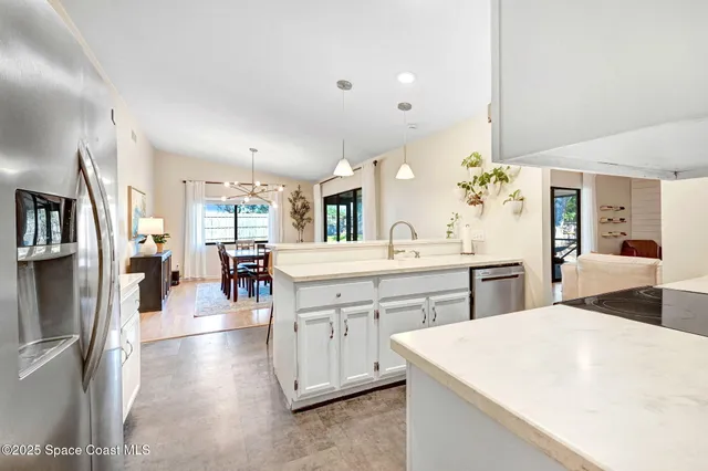 a large white kitchen with a lot of counter space and wooden floor