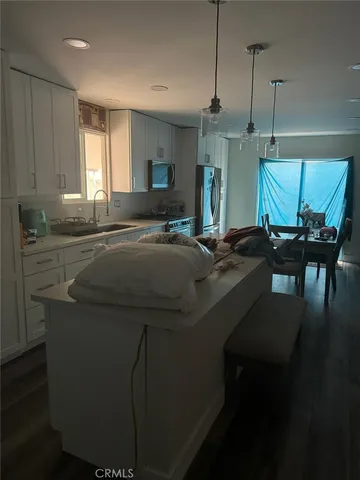 a kitchen with kitchen island granite countertop a sink a stove a refrigerator and chairs