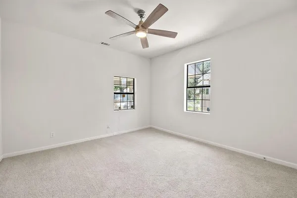 an empty room with windows and fan