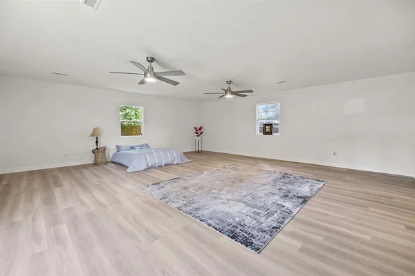 a view of a bedroom with wooden floor and a ceiling fan