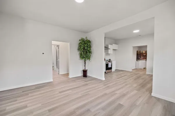 a view of a room with wooden floor and a refrigerator