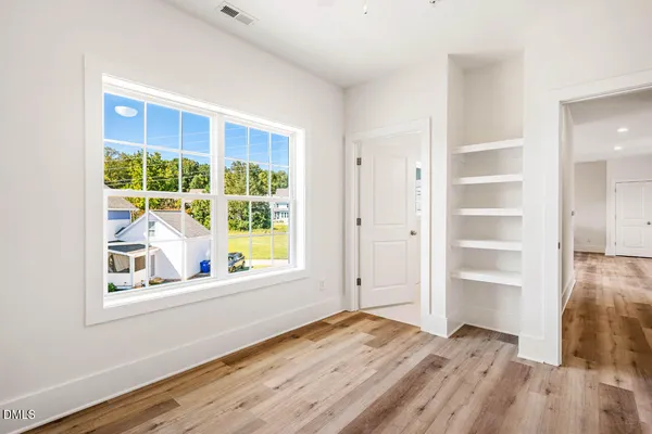 a view of an empty room with a window and wooden floor
