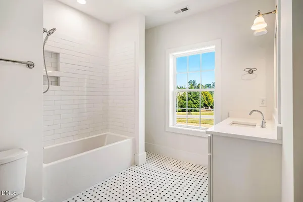 a bathroom with a granite countertop bathtub a sink and a window