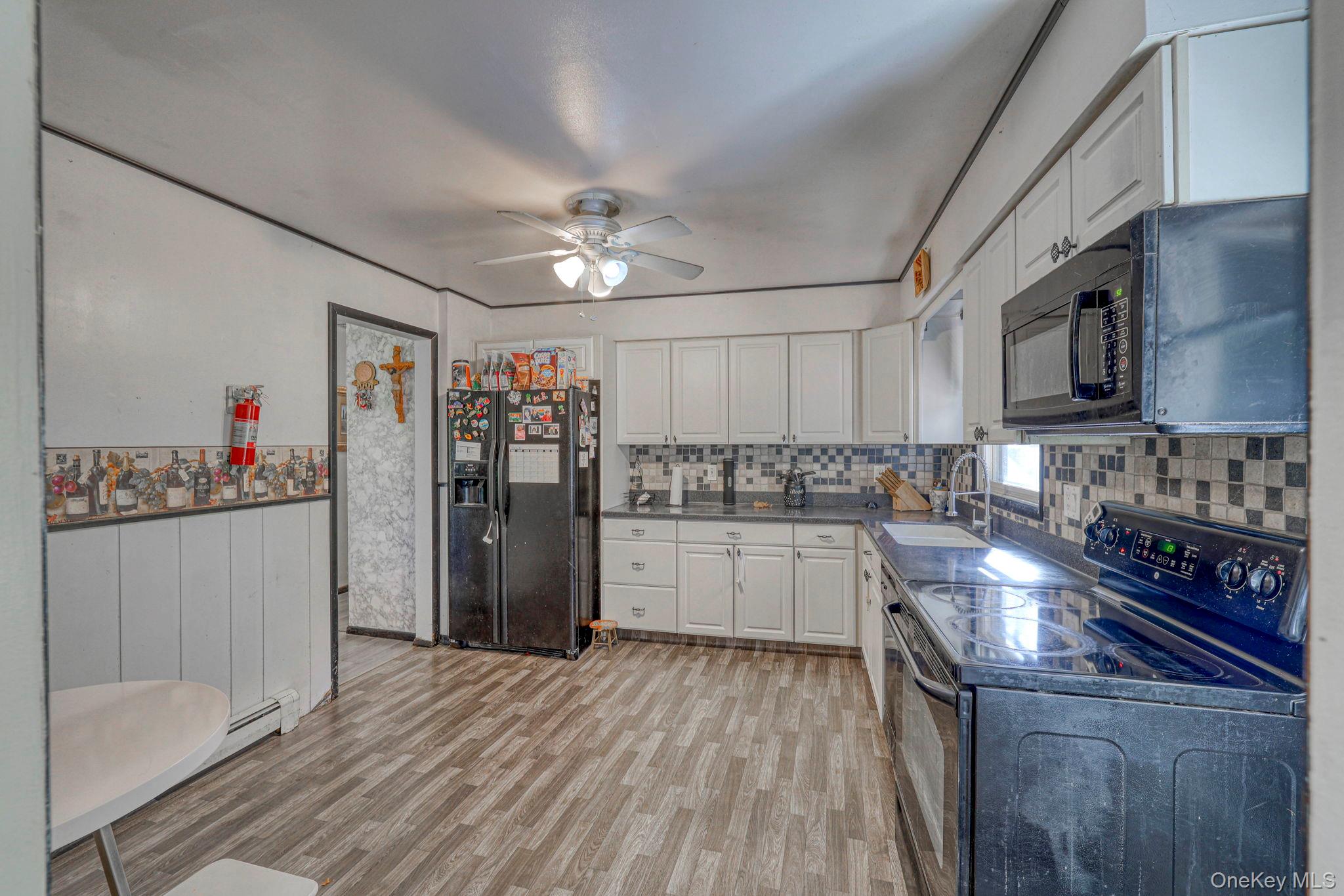 191 Mills Road Walden, NY 12586 - Photo 13 of 27 Kitchen with black appliances, light wood-type flooring, white cabinets, ceiling fan, and tasteful backsplash