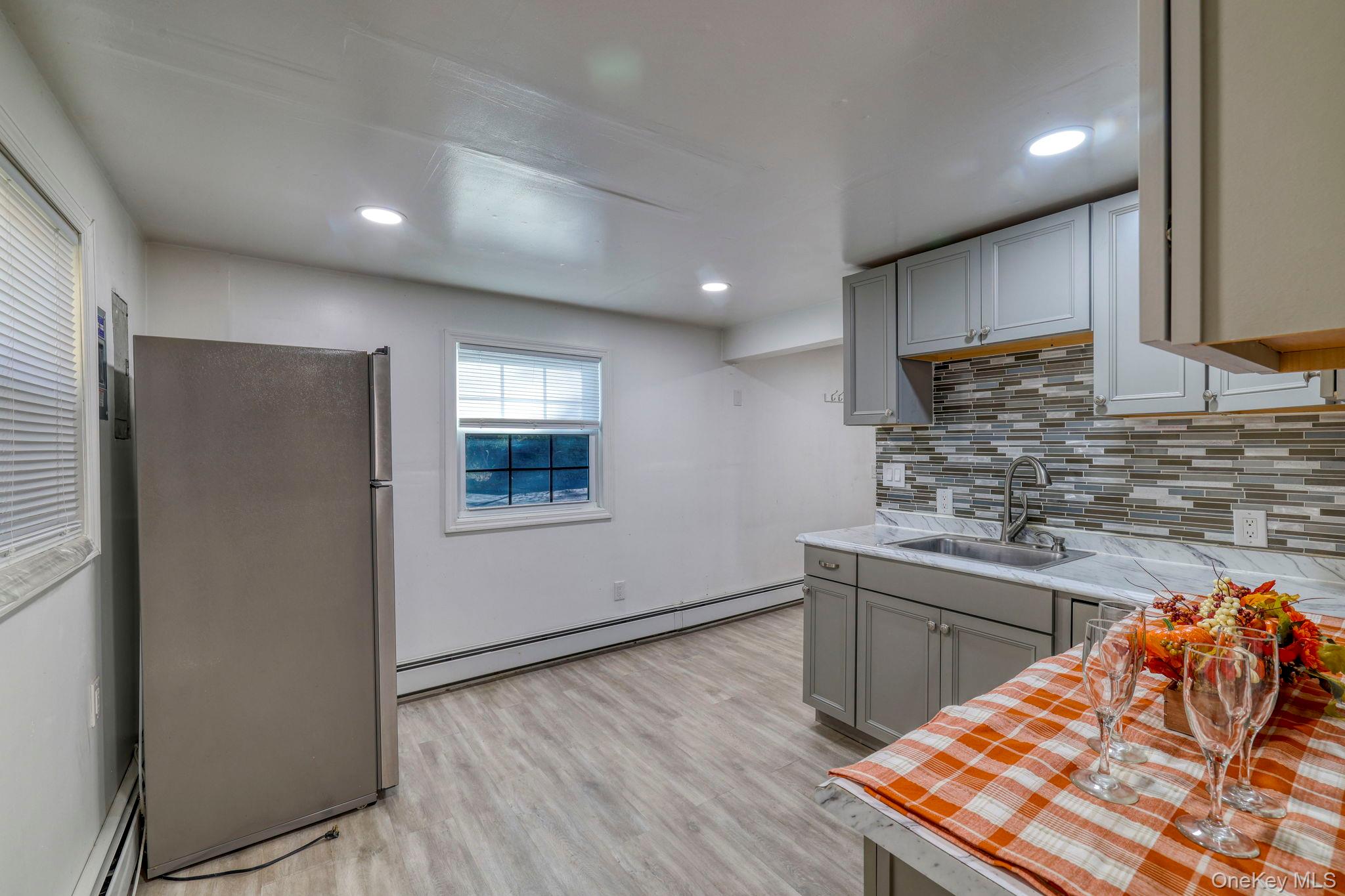 191 Mills Road Walden, NY 12586 - Photo 26 of 27 Kitchen with tasteful backsplash, freestanding refrigerator, light countertops, a baseboard radiator, and gray cabinets