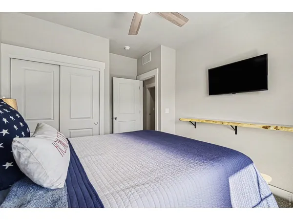 a bedroom with a bed next to a window with a chandelier
