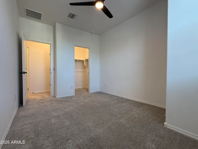 an empty room with ceiling fan and windows