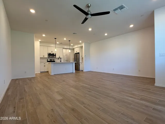 a kitchen with stainless steel appliances granite countertop a refrigerator a sink a stove and a wooden floors