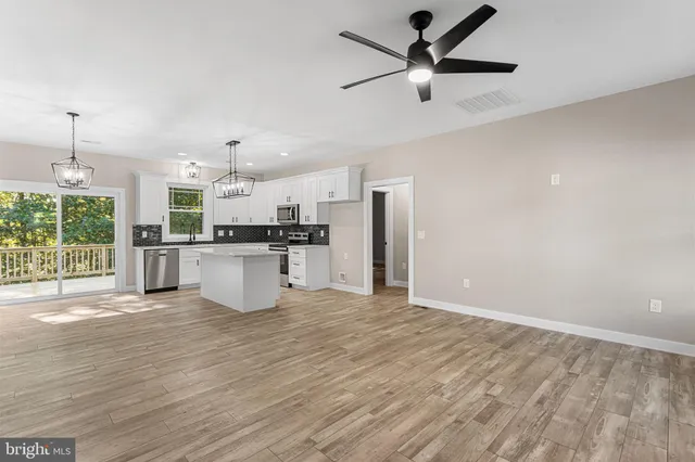a view of kitchen with stainless steel appliances wooden floor and a window