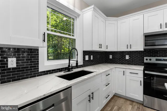 a kitchen with granite countertop white cabinets and window