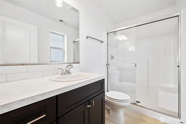 a bathroom with a sink a toilet a mirror and shower