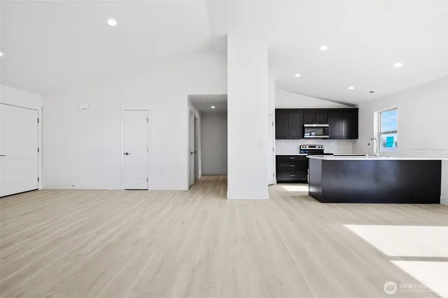 a view of kitchen with stainless steel appliances wooden floor and large window