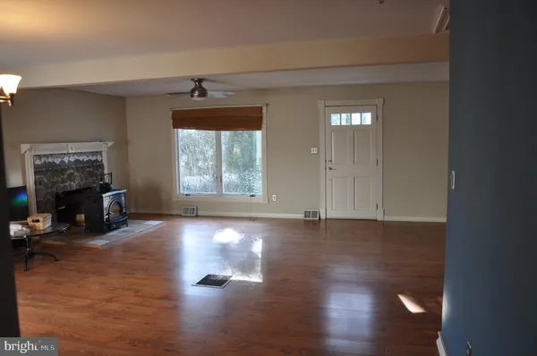 an empty room with wooden floor cabinet and windows